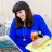 Pixelated image of a person with long dark hair wearing a blue top, holding an orange object against a blurred background.