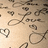 Pixelated image with scattered dark brown and gray shapes on a light beige background, including partial heart outlines and curved lines.