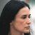 Pixelated close-up of a person's face in profile view with dark hair, light skin tone, and closed eyes against a blurred background.