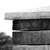Static grayscale image showing a partial view of a dark rectangular shape with lighter horizontal bands against a white background.