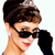Pixelated close-up of a person with short brown hair wearing dark sunglasses, red lipstick, and a black sleeve, against a white background.