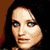 Pixelated static image of a person's face with dark hair and light skin tones against a brown background.