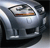 Pixelated silver car with visible headlights and grille, set against dark background with light reflections.