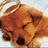 A pixelated close-up of a brown dog's face with dark eyes and nose, set against a light blue background.