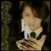 A person in a dark suit and white shirt holds a candle with blue flame, standing against a background of vertical text reading "light me up".