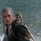 Animated sequence of a person with long blonde hair in dark clothing against a water background, showing head and body movement.