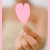 A hand holds a pink heart-shaped object against a light background with text overlays changing across frames.