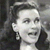 Pixelated grayscale image of a person with short dark hair, wearing a dark top, holding a dark object near their face.