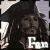Pixelated grayscale image of a person with long dark hair wearing a wide-brimmed hat, standing against a light background with partial text visible at the bottom right.
