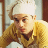 Pixelated static image of a person wearing a white chef's hat and yellow jacket with brown accents, set against an indistinct background.
