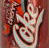 Pixelated static icon with abstract swirling patterns in muted reds, browns, and off-whites on a dark reddish-brown background.