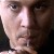 Pixelated close-up of a person's face showing eyes, nose, and mouth with light skin tone and dark hair against a dark background.