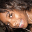 A close-up of a person's face with light skin tone, dark hair, and visible eye details against a blurred background.