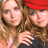 Two side-by-side animated frames showing two women with long brown hair, one wearing a red cap and dark top, the other in light clothing, next to stylized text reading "NEW YORK MINUTE" on black background.