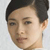 A pixelated close-up of a person's face with short dark hair, neutral expression, and light skin tone against a plain light background.