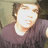 Pixelated static image of a person with light brown hair wearing a dark purple shirt against a muted background.