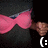 Pixelated image of a figure with pink hair and a dark outfit, holding a brown object, with a white smiley face symbol in the corner.