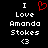 Black background with white pixelated text reading "I Love Amanda Stokes <3" and a red pixelated heart symbol above the text.