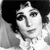 Black-and-white pixelated image of a person with dark hair styled in a high bun, wearing a light-colored garment with a high collar.