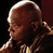 Pixelated close-up of a bald character's head and shoulder in profile, with visible facial features against dark background.