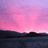 Pixelated landscape with pink-purple sky over dark water and hills, overlaid with red pixelated text on black background.