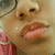 A close-up of a person's face with pink clothing and glasses, showing subtle mouth movement across frames.