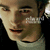 Static pixelated image of a person's face with light skin tone, dark eyebrows, and dark eyes, wearing a light-colored shirt against a dark background.