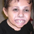 A pixelated close-up of a person with light skin wearing a dark shirt, showing the head and upper neck against a blurred background.