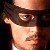 Pixelated close-up of a person's face with dark hair, wearing a dark cap, against a dark background.