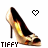 Two side-by-side pixelated high-heeled shoes with black interiors and gold exteriors, each labeled 'TIFFY' below, one with a white heart icon above the left shoe.