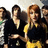 A pixelated group of five people in formal attire, with a woman in yellow and black at the center.