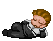Pixelated character with brown hair lies on gray background, wearing dark suit and white shirt; first frame shows left arm extended, second frame shows right hand near face.