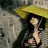 Pixelated image of a person with long dark hair holding a yellow umbrella against a muted background.