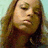 A pixelated image of a person with long brown hair against a light blue background, featuring text at the bottom right.