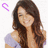 Pixelated image of a woman with long brown hair wearing an off-shoulder purple top, surrounded by pink text and a small purple symbol.