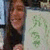 A person with long dark hair holds a light-colored paper displaying green Chinese characters, while pink text overlays read "Hilarious self portrait" and "Priceless.".