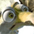 Pixelated cartoon character with large green eyes, gray body, and yellow beak-like mouth, set against a light background.
