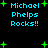 Pixelated cyan text "Michael Phelps Rocks!!" with green plus symbols on black background, two identical copies arranged in a pattern