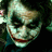 A pixelated image of a character with white face paint, dark eye makeup, and red lips smiling against a black background with red text.