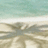 Pixelated static image showing a beach scene with light blue sky, white sand, and blurred brownish shapes resembling trees or structures on the shore.
