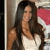 A pixelated image shows a person with long dark hair wearing a white sleeveless top, standing near a pink and white object against a neutral background.