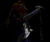 Animated sequence of a person with long hair singing into a microphone, wearing dark jacket and white shirt against black background.