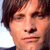 Pixelated close-up of a person's face with brown hair, light skin, and a neutral expression against a light background.
