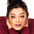 A pixelated close-up of a person with dark hair styled in an updo, wearing a maroon garment against a white background.