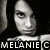 Black-and-white pixelated image of a person with dark hair, wearing a light-colored top and necklace, with text "MELANIE C" at the bottom left.