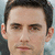 Static pixelated image of a person's face with short dark hair, light skin tone, and neutral expression against blurred background.