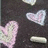 Pixelated static image with four distinct shapes on dark background: pink heart, white heart, light gray oval, and pale rounded shape.