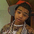 A person wearing a red and gray cap and a patterned shirt with a white necklace, shown in four with slight head and eye movement
