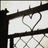 Black metal fence with barbed wire and a heart-shaped cutout on white background.