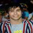 Pixelated image of a person with light skin wearing a striped shirt, smiling against a dark background.
